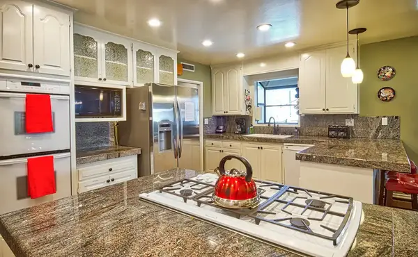 Full white kitchen with granite island and red stools